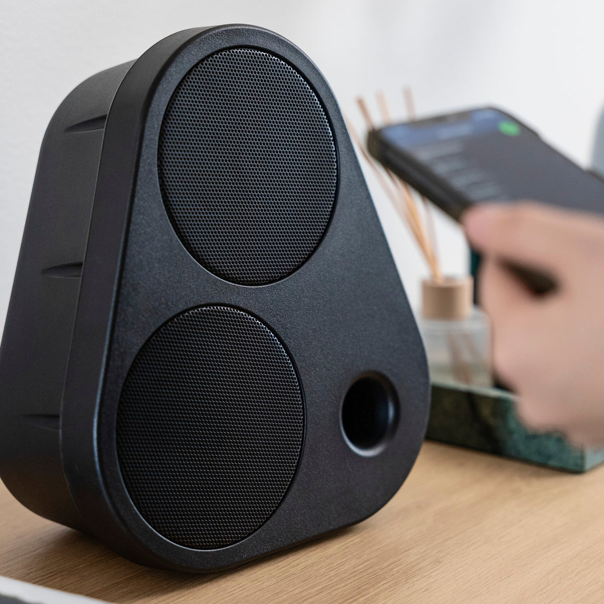 Schwarzer ES2 auf einem Holztisch neben einem Smartphone #color_black