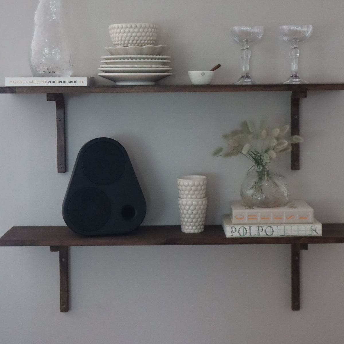 Schwarzer ES2 auf einem Wandregal mit Geschirr und Büchern #color_black
